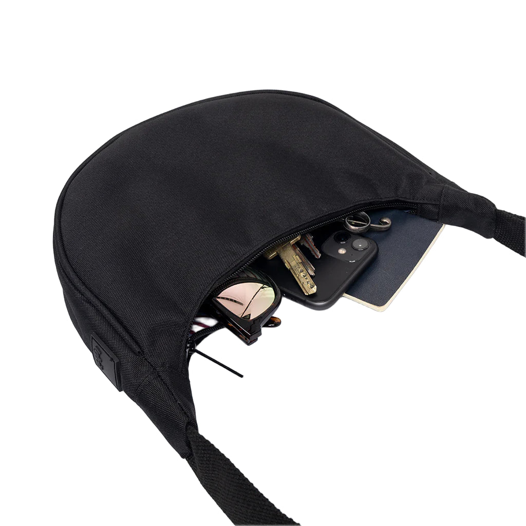 Bolso negro con forma de media luna de la marca española Lefrik con la cremallera abierta del que asoman varias cosas como gafas de sol, llaves o un móvil