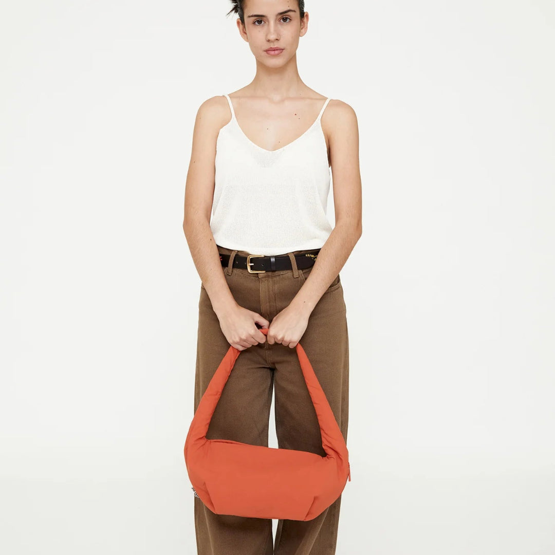 Mujer con pantalón marrón sujetando el bolso mini naranja acolchado de lefrik