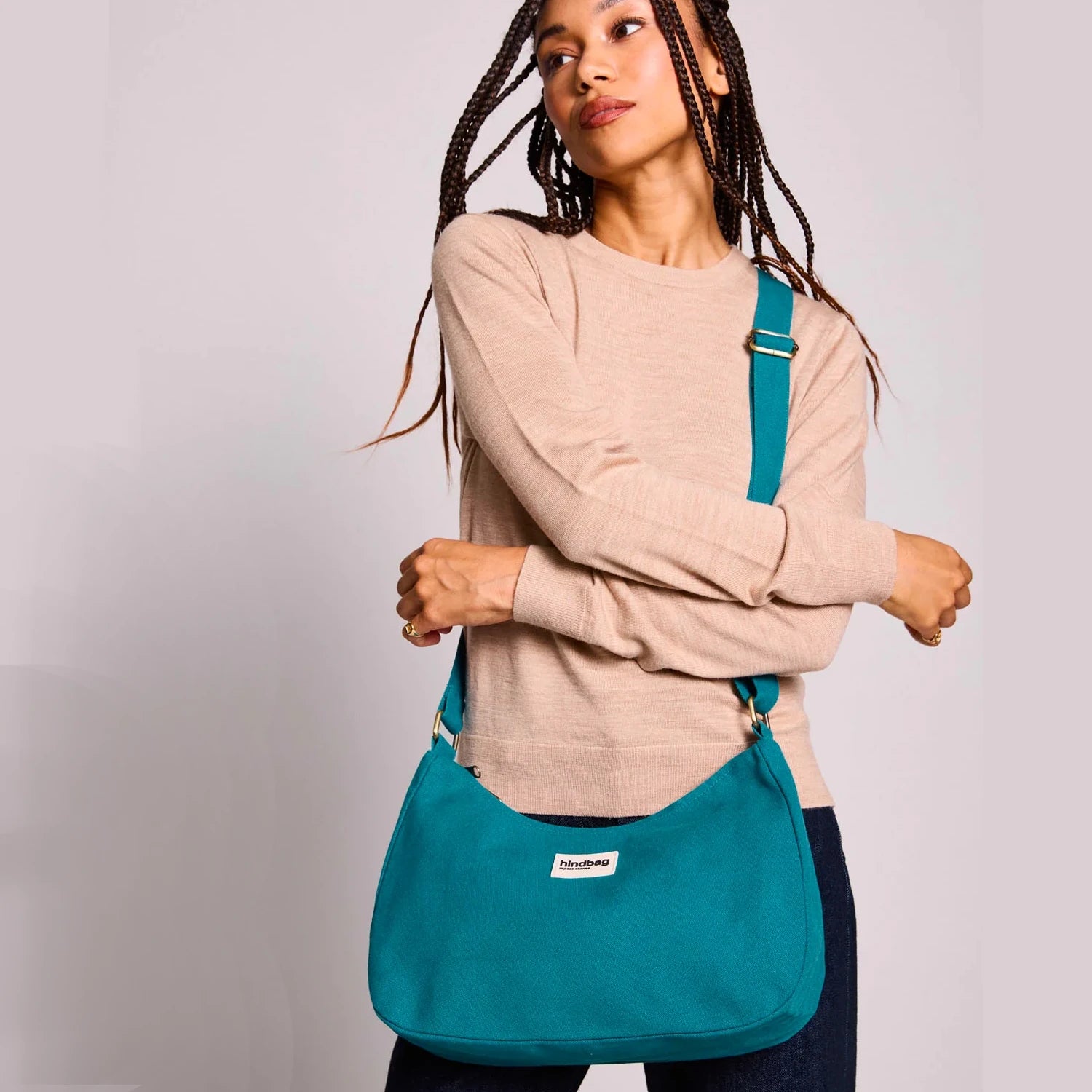 Mujer con trenzas en el pelo y un bolso de hombro azul turquesa de la marca francesa Hindbag