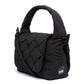 Vista lateral del bolso negro Ani de Lefrik, con detalle de la solapa trenzada, el asa acolchada y la etiqueta de la marca.

