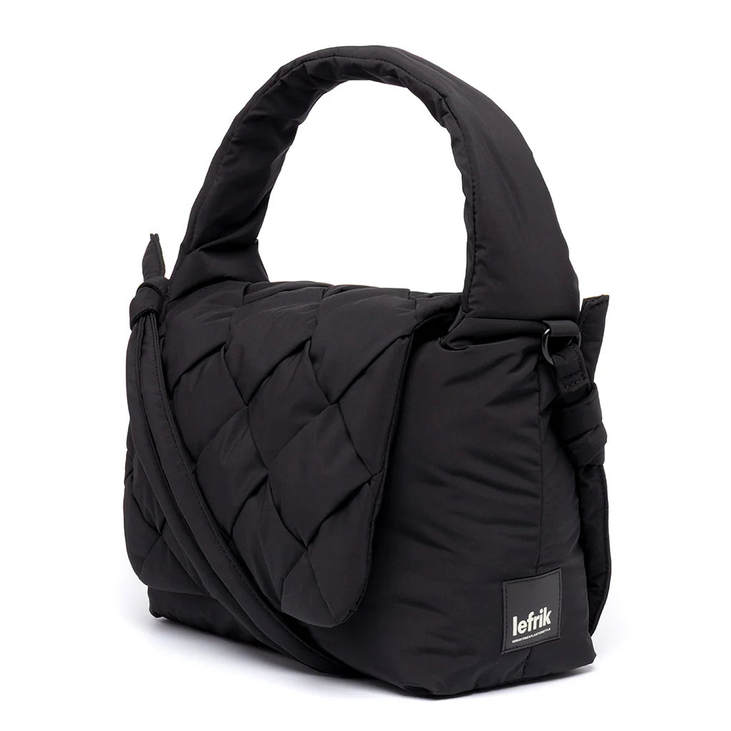 Vista lateral del bolso negro Ani de Lefrik, con detalle de la solapa trenzada, el asa acolchada y la etiqueta de la marca.

