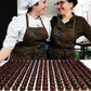 dos cocineras de Utopick Cacao en frente de una mesa llena de bombones rellenos de cremaet