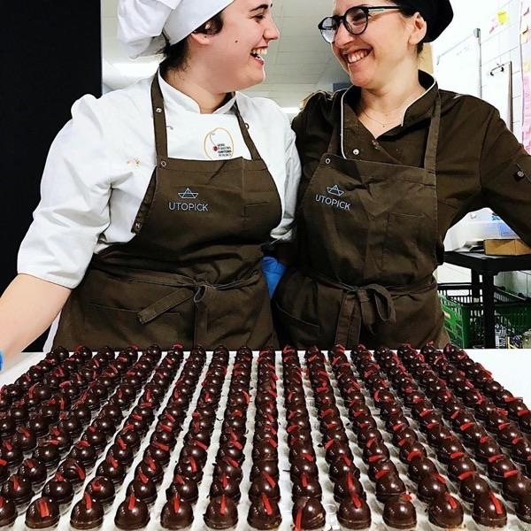 dos cocineras de Utopick Cacao en frente de una mesa llena de bombones rellenos de cremaet