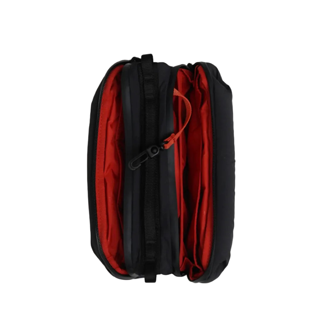 Interior del bolso Bottle Sacoche Medium Topologie en color negro con forro rojo y mosquetón naranja, visto desde arriba con las cremalleras abiertas