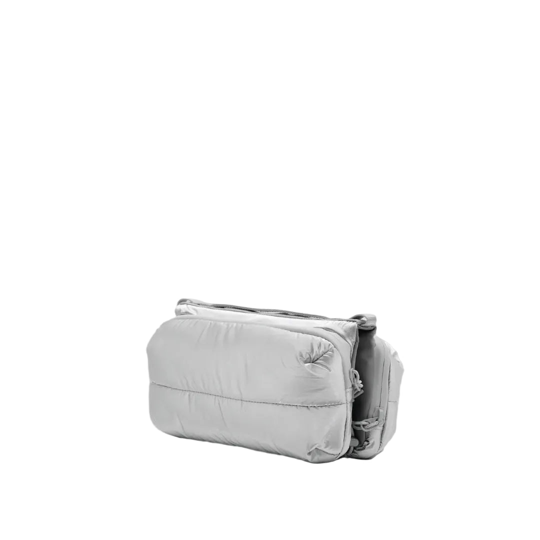 Bolso Bottle Sacoche Medium Topologie en color plateado Space Coated, vista en ángulo de tres cuartos con detalle del compartimento lateral para botella