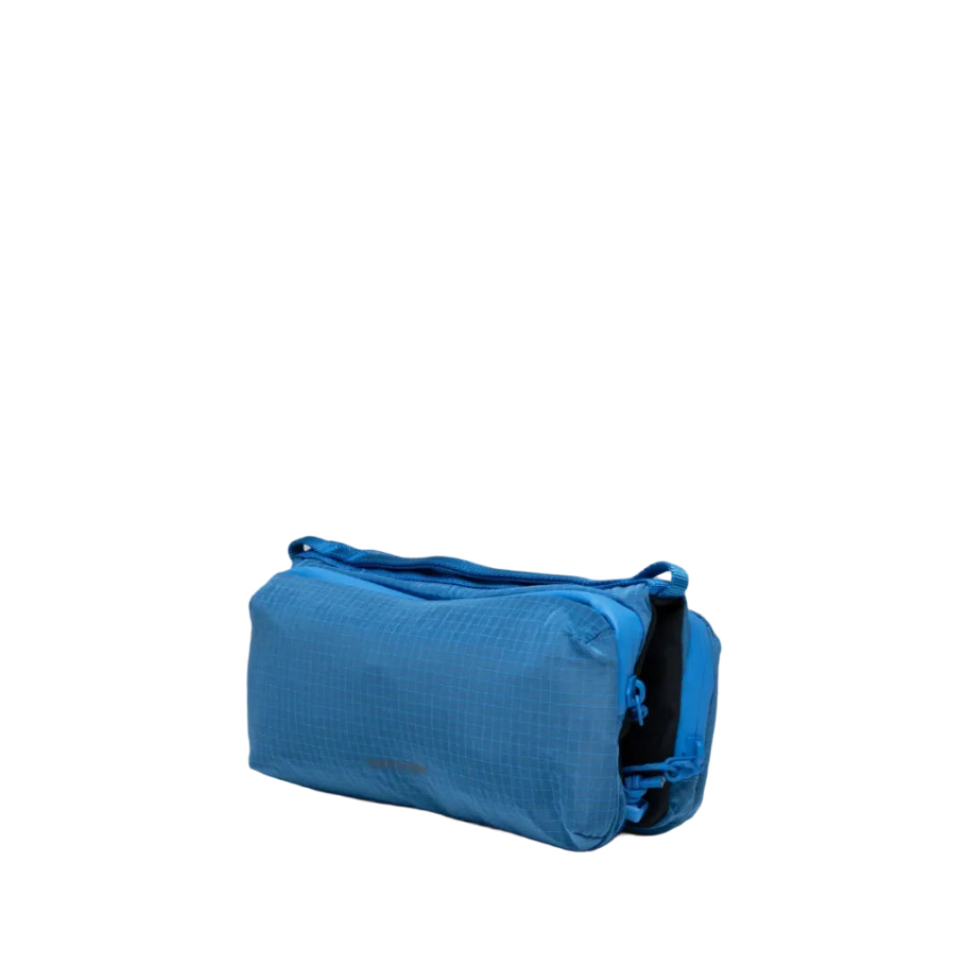 Bolso Bottle Sacoche Medium Topologie en color azul Sonic Vintage Ripstop, vista lateral en perspectiva con compartimento inferior para botella visible en negro
