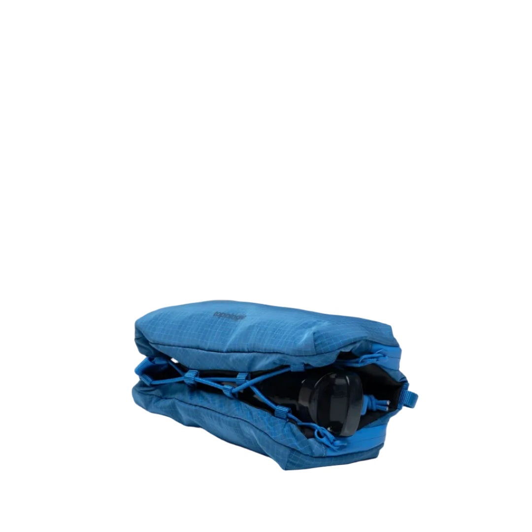 Bolso Bottle Sacoche Medium Topologie en color azul Sonic Vintage Ripstop visto desde arriba, con compartimento inferior abierto y botella de agua negra asomando
