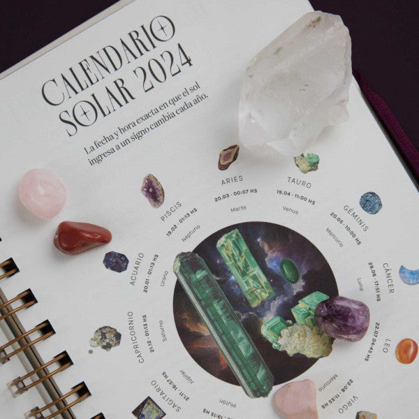 Varias piedras y cristales sobre el calendario solar de la agenda de la Bruja Moderna Dalia F Walker para 2024
