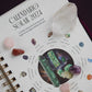 Varias piedras y cristales sobre el calendario solar de la agenda de la Bruja Moderna Dalia F Walker para 2024