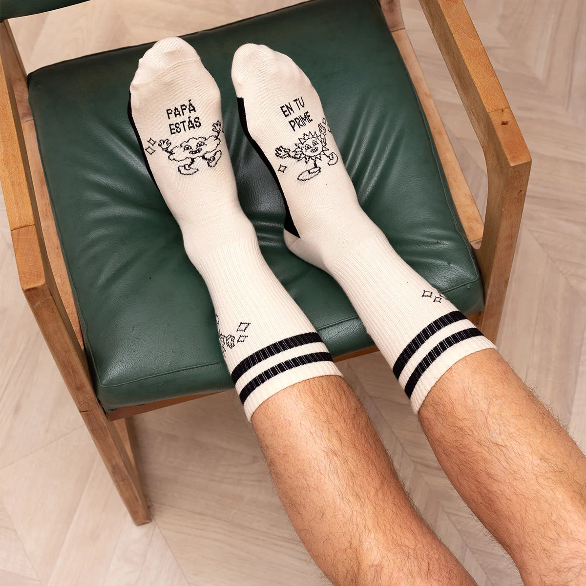 modelo posando con los calcetines con el texto "papá estás en tu prime" en color blanco y negro