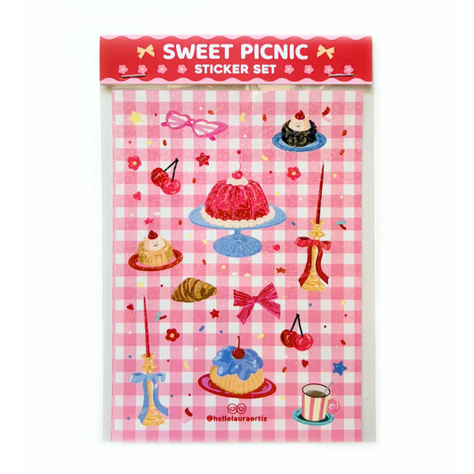 pack de pegatinas con el texto sweet picnic sticker set con una hoja de pegatinas que tiene pasteles con caritas, una tarta de gelatina, candelabros, una taza de café, cerezas, gafas en forma de corazón sobre un fondo a cuadros rosas y blancos imitando un mantel de picnic