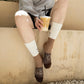 Persona sentada con los calcetines UO «Café, luego existo» puestos y un vaso de café con hielo en la mano.