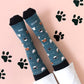 Pies con los calcetines de UO con estampado de gatos y el mensaje Amor Gatuno sobre un rastro de huellas de gato pintadas en el suelo rosa