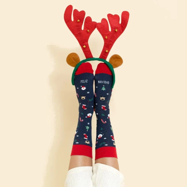 Pies con los calcetines de Feliz Navidad y una diadema de orejas de reno