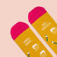 Detalle de la puntera rosa de los calcetines mostaza con estampado de cervezas y banderillas y el mensaje menos drama, más cerveza
