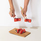 Tabla con los calcetines Tienes Rollazo de UO con los colores del sushi enrollados y dos manos cogiéndolos con palillos chinos