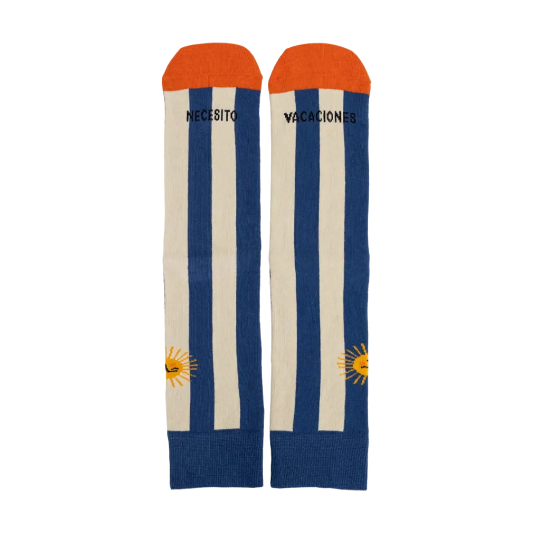 calcetines a rayas verticales azules y puntera naranja con dibujo de un sol y el texto "Necesito vacaciones"
