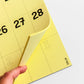 Detalle del calendario de pared amarillo con números grandes y espacio para escribir de Colla Paper