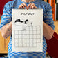 Chico con camiseta a rayas azules sosteniendo el calendario 2027 ilustrado por Helen B abierto por el mes de julio, con ilustración de una chica en bañador en postura acrobática sosteniendo unas flores con los pies
