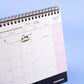 Detalle del calendario de mesa 2027 con ilustraciones de la serie Macanudo de Liniers en el mes de mayo