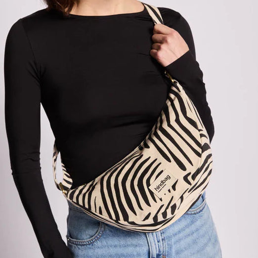 Persona que lleva un bolso de la marca Hindbag modelo Andrea con estampado de cebra y fondo crema. 