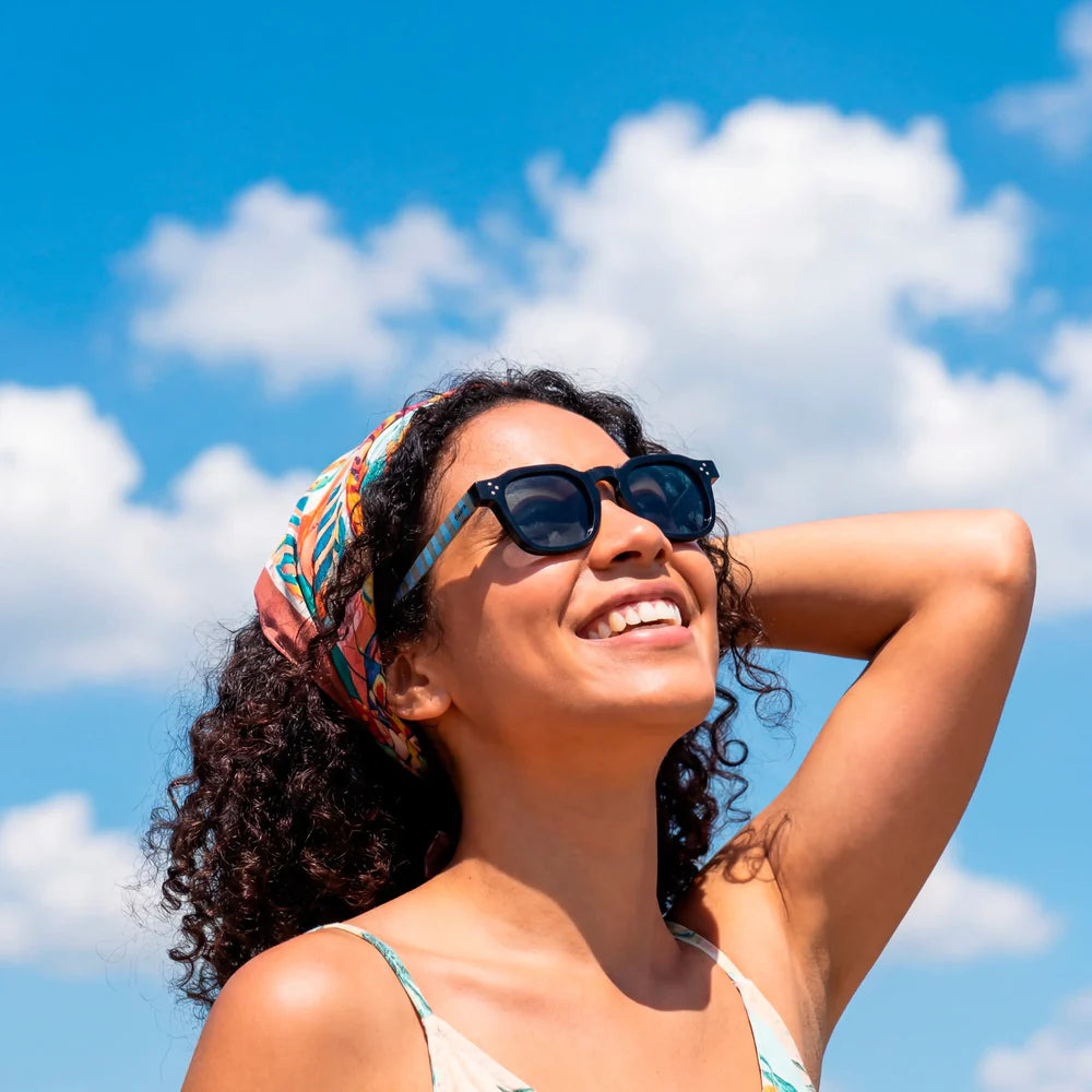 modelo posando con las gafas de sol de Fisura redondas en color negro con las patillas a rayas azules y marrón, del modelo "Modo Chiringuito"