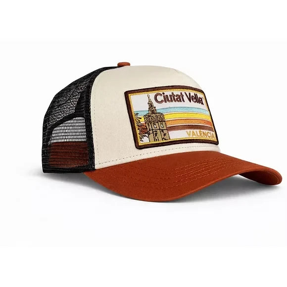 Vista lateral de gorra de Blocals con las letras Ciutat Vella València y dibujo de torre. Parte delantera blanca y visera marrón con laterales de rejilla negra.