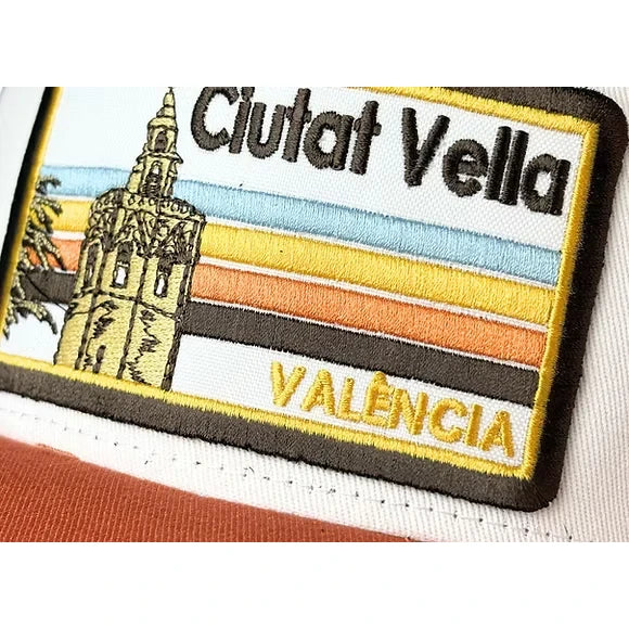 Detalle de gorra de Blocals con las letras Ciutat Vella València y dibujo de torre. Parte delantera blanca y visera marrón.