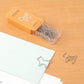 Escritorio con papeles u clips de metal con forma de perrito de la firma japonesa Midori