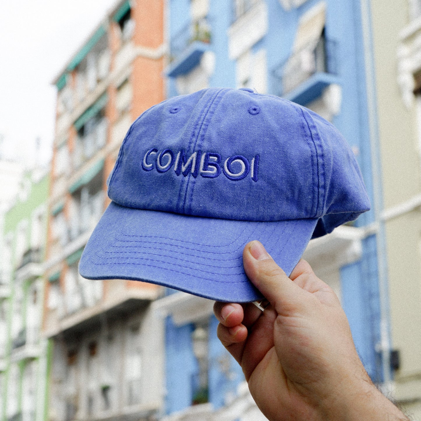 Gorra azul con la palabra Cmboi frente a fachadas modernistas del barrio de Ruzafa