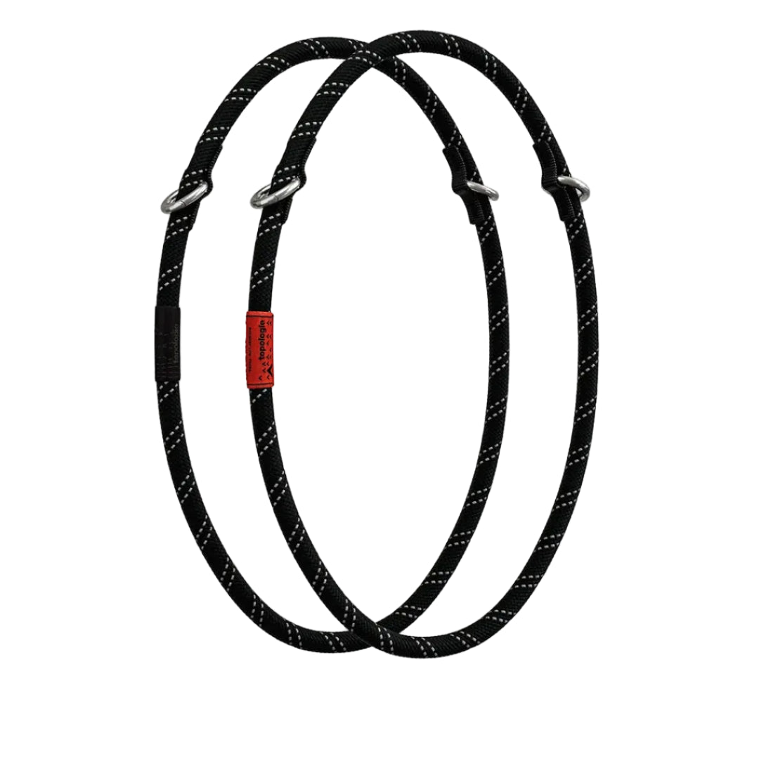Dos correas Loop negras reflectantes de 10mm Topologie enrolladas en forma de óvalo sobre fondo blanco, con etiqueta roja de la marca y anillas metálicas