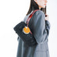 Modelo con bolso negro al hombro sujeto con correa Loop rosa de 10mm Topologie, vista lateral con americana gris