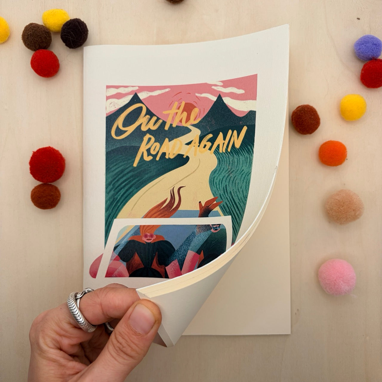 Libreta con portada ilustrada con una pareja en un coche de frente con el camino y las montañas de fondo y hojas en blanco