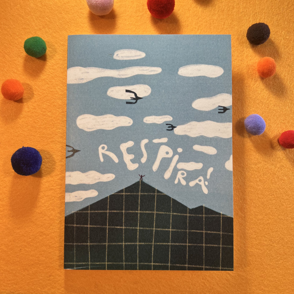 Cuaderno tamaño A5 con ilustración de un cielo lleno de nubes y pájaros y una persona sobre la cima de una montaña con los brazos abiertos
