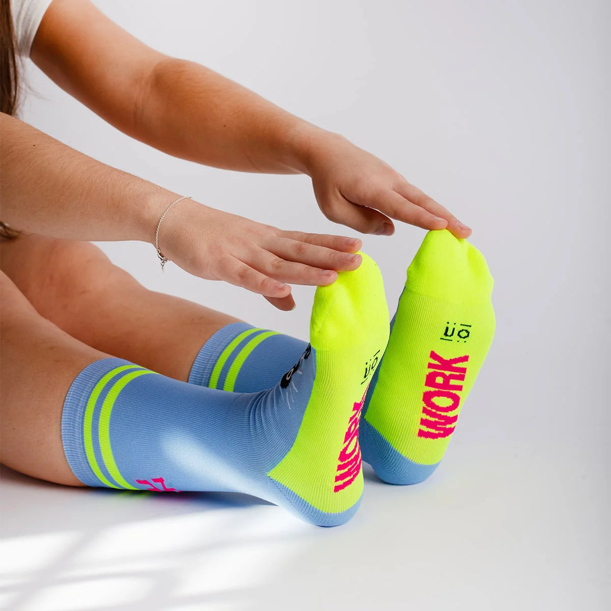 Chica estirando con los calcetines deportivos azules con el mensaje "Calcetines para darlo todo" work en la planta y yes girl you can