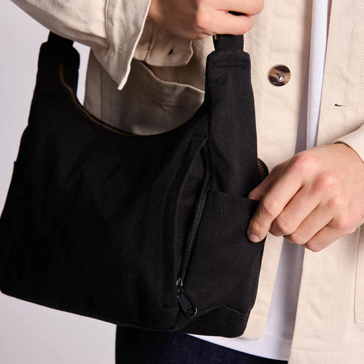 Persona sujeta el bolso Emile de la marca Hindbag en negro, donde se ve uno de los bolsillos de la parte trasera. 