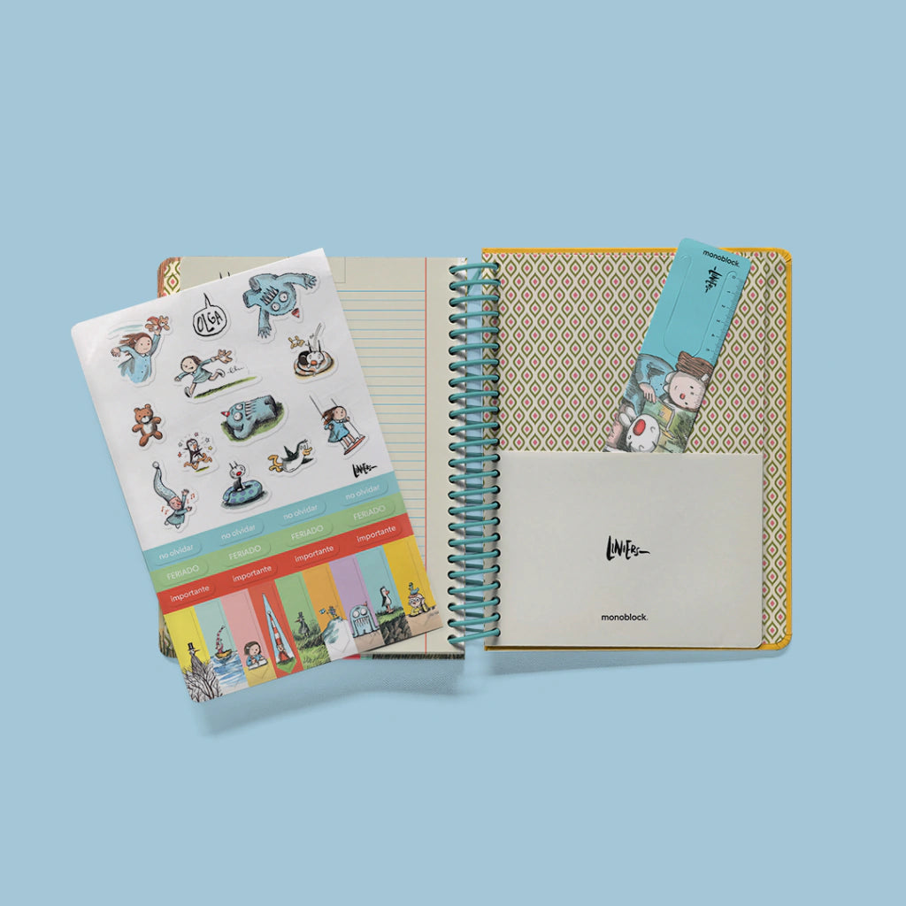 Agenda semanal 2027 Macanudo abierta mostrando hoja de pegatinas funcionales con personajes de Liniers y marcapáginas con regla