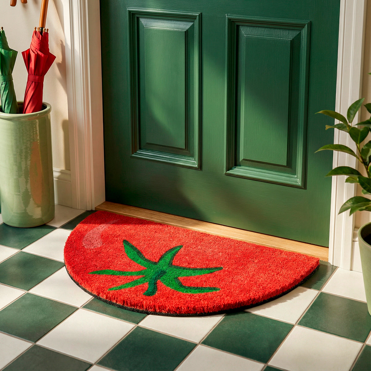Puerta verde con paragüero y maceta al lado y un felpudo con forma de medio tomate sobre suelo a cuadros verdes y blancos