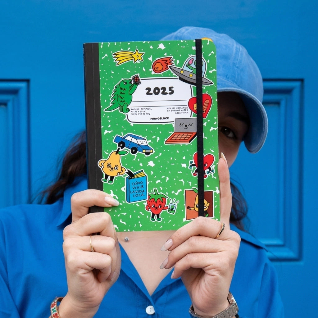 Mujer con gorra delante de una puerta azul con la agenda 2025 de la artista argentina Flo Meije Stickers, con dibujitos