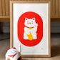 Serigrafía enmarcada de estilo japonés con un Maneki Neko rojo y blanco sobre fondo rojo. 