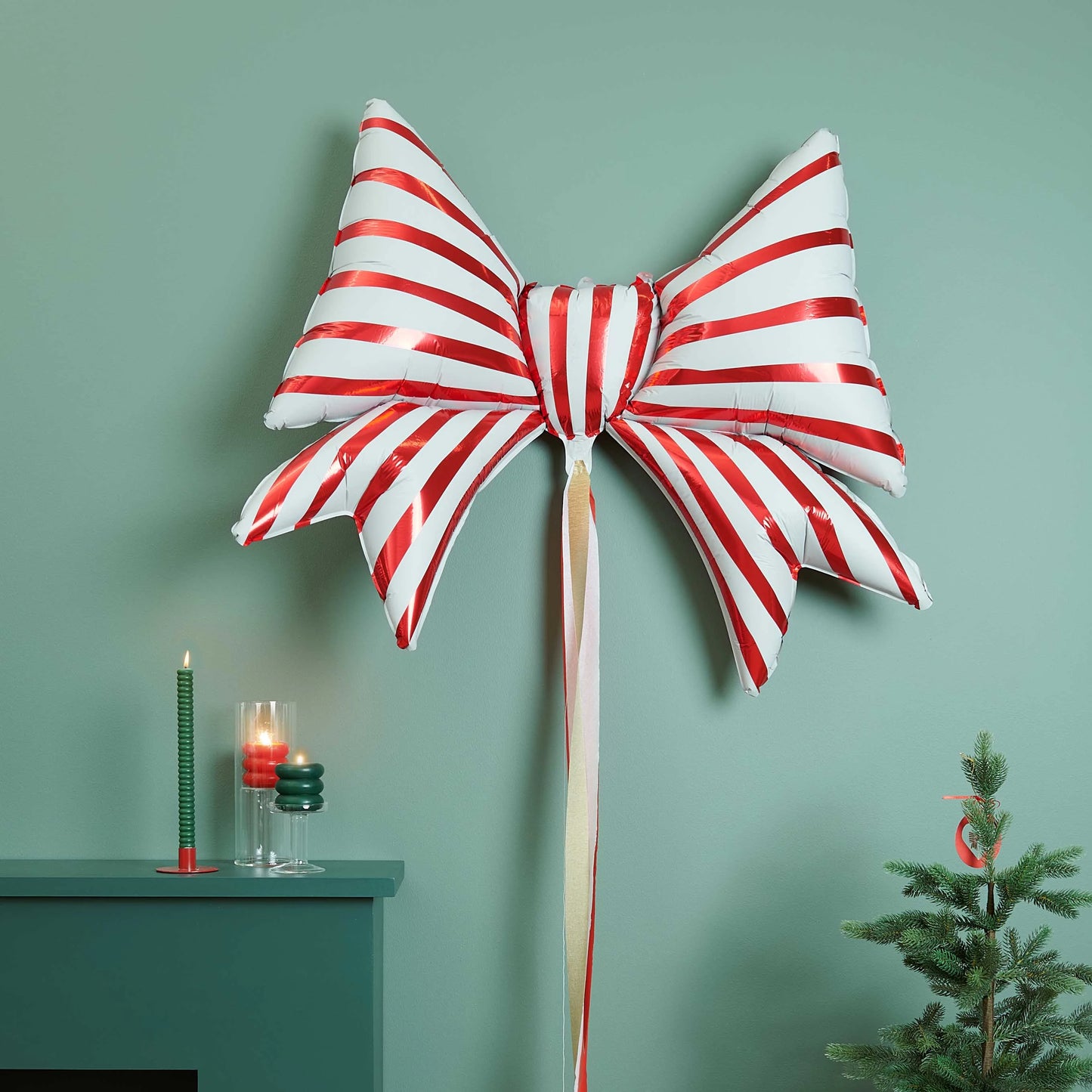 globo en forma de lazo con rayas blancas y rojas, hinchado y puesto sobre una pared con decoraciones navideñas