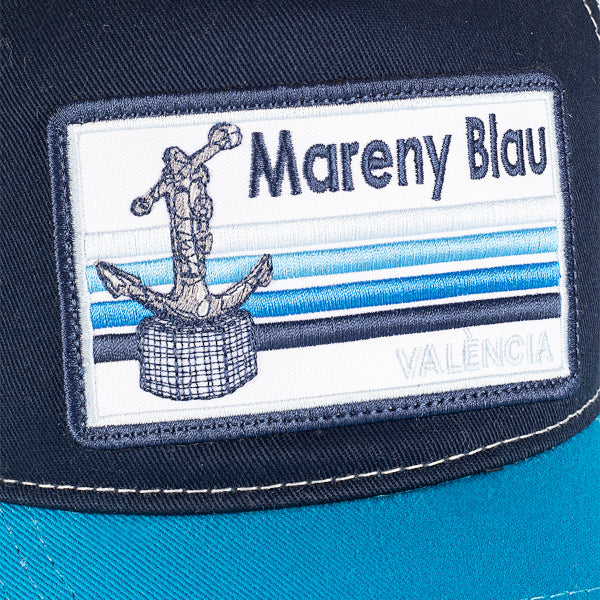 Detalle de la gorra con visera en azul mariono y azul claro con parche de la playa de Mareny Blau, en Valencia
