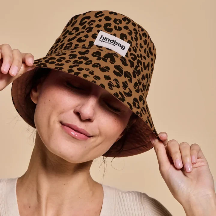 Mujer con un gorro de pescador de tejido orgánico estampado con manchas de leopardo sobre fondo canela de la marca francesa Hindbag