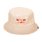 gorro de pescador de tela reversible en color beige con la frase "no me da la vida" bordada en letras de colores