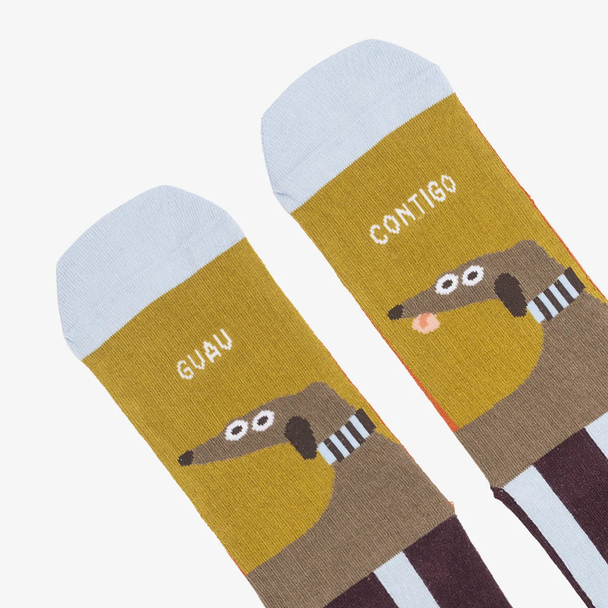 Detalle de los calcetines GUAU contigo de UO, con perros marrones sobre fondo mostaza y el mensaje «GUAU CONTIGO».