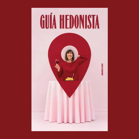 Portada del anuario Guía Hedonista 2025 con una chica ante un plato de bravas con una copa de vino en la mano formando el marcador de geolocalización