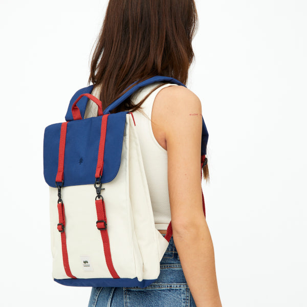 Chica de espaldas con la mochila Bauhaus de Lefrik en azul marino y crema con correas rojas y cierre con mosquetones 100% reciclada