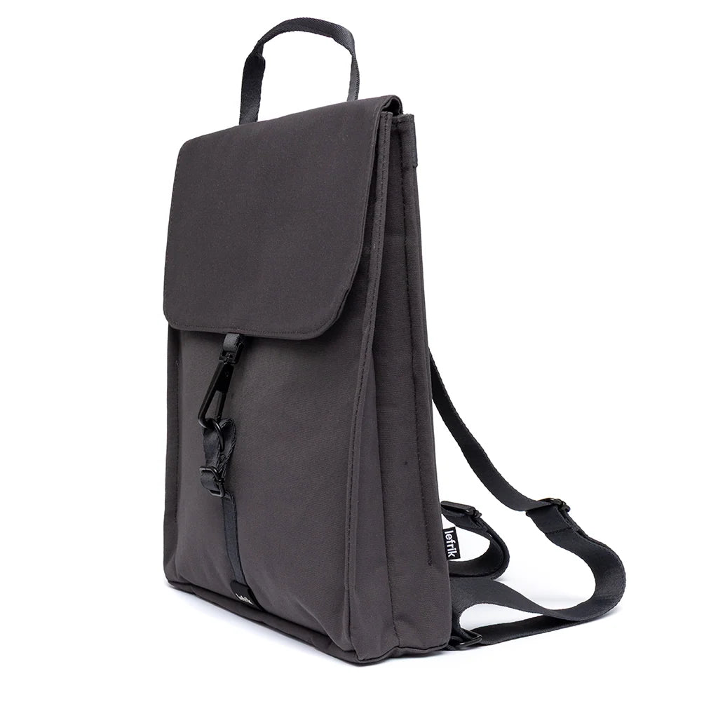 Vista lateral de la mochila plana y compacta de tejido reciclado e impermeable en color gris cemento y con cierre de mosquetón de la marca española Lefrik 