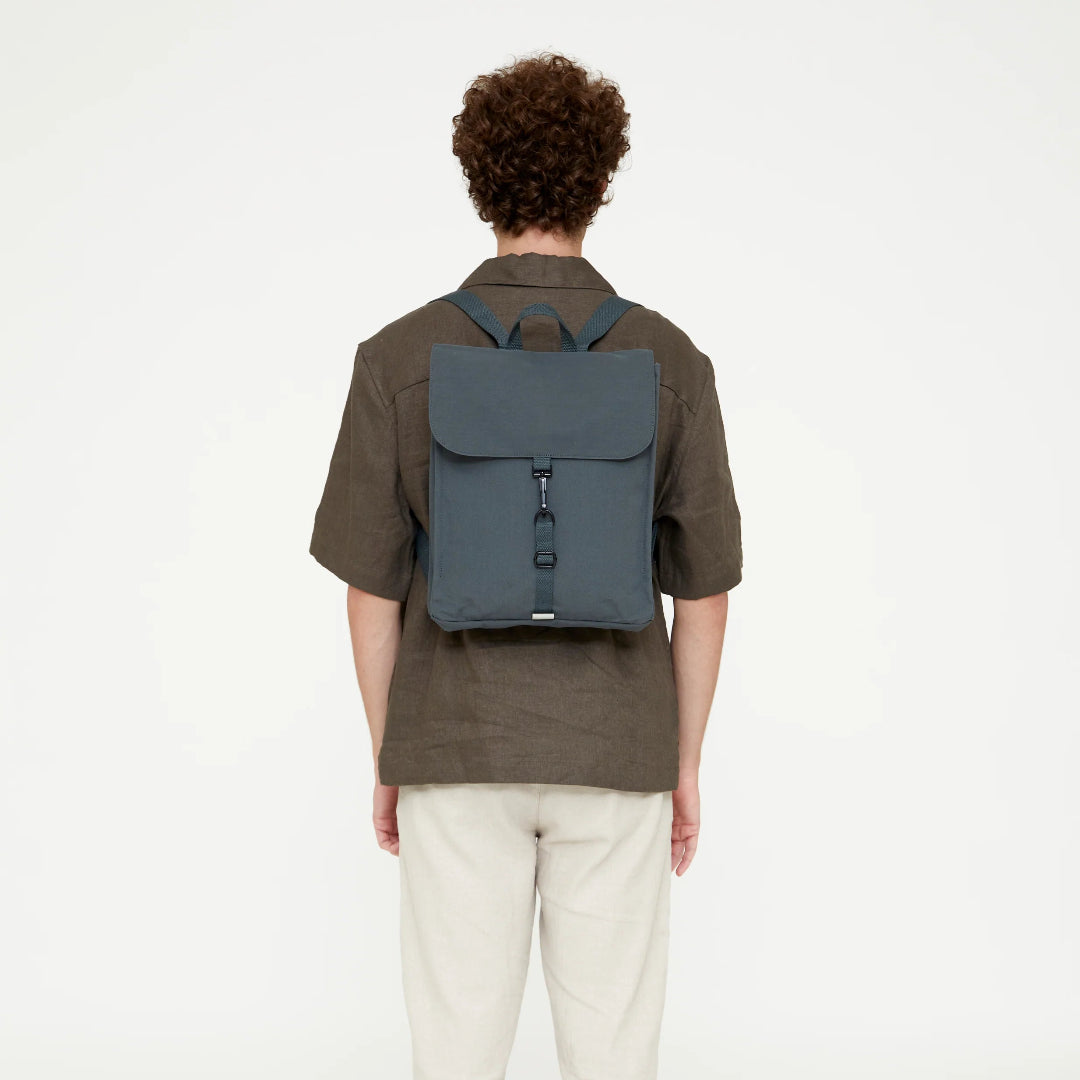 Vista trasera de modelo masculino llevando la mochila Lefrik gris pizarra a la espalda, mostrando el ajuste de las correas