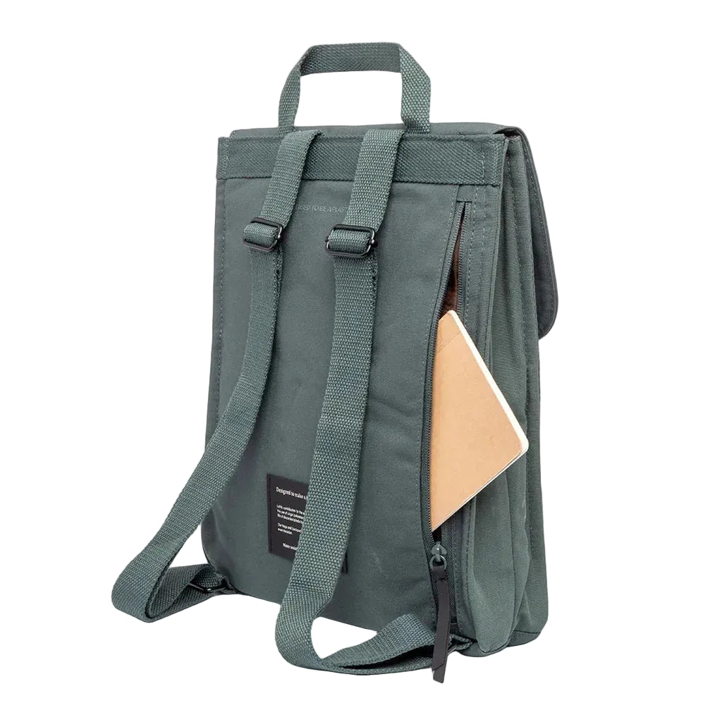 Vista trasera en ángulo de la mochila Lefrik verde salvia con bolsillo lateral abierto y libreta asomando, correas ajustables visibles